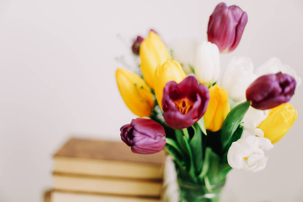 Bouquet di bellissimi tulipani. Mix di fiori di tulipani primaverili. Freschi fiori primaverili e libri su sfondo bianco
.  - Foto, immagini