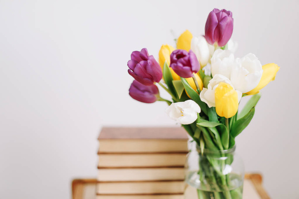 Bouquet of beautiful tulips. Mix of spring tulips flowers. Fresh spring flowers and books on white background.  - Photo, image