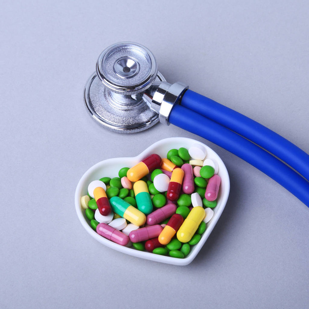 Stethoscope, RX prescription and colorful assortment pills and capsules on plate. - Фото, изображение
