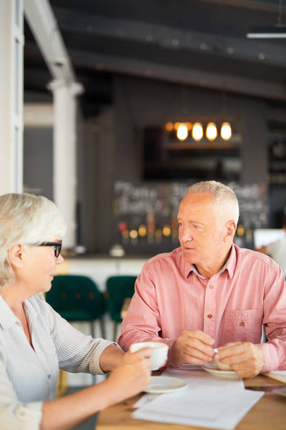 Homme d'affaires et femme d'affaires assis à table dans un café et discuter des nouvelles par tasse de thé
 - Photo, image