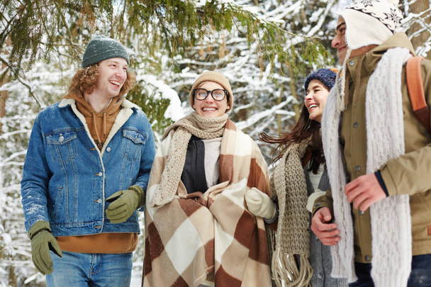 Portret czterech szczęśliwych młodych ludzi w ośrodku zimowym stwarzających w ośnieżonym lesie i uśmiechnięty wesostowo - Zdjęcie, obraz