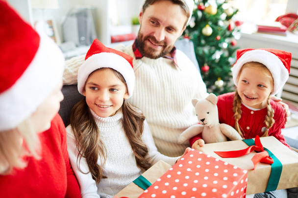Досить брати і сестри, їх мама і тато в шапочках Санта обговорюють плани на різдвяні канікули
 - Фото, зображення