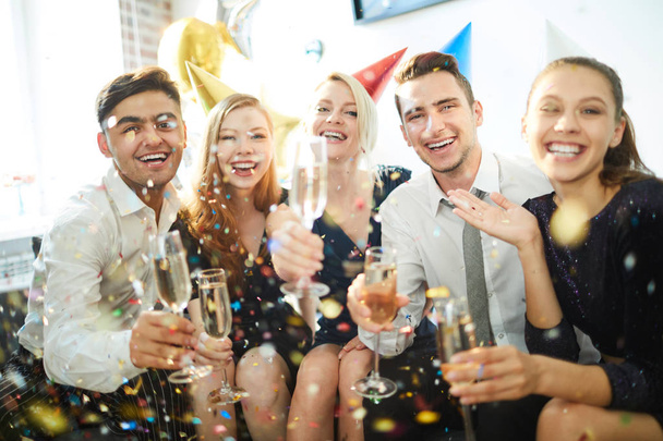 Grupa młodych śmiech przyjaciół z szampanem wyrażając radość podczas domowego przyjęcia urodzinowego - Zdjęcie, obraz