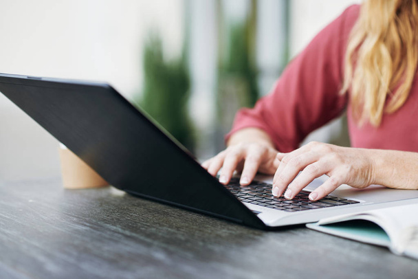 Zbliżenie: kobiece dłonie, wpisując na klawiaturze laptopa przy stole na świeżym powietrzu - Zdjęcie, obraz