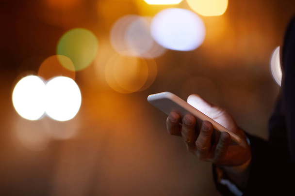 Mano de hombre de negocios móvil sosteniendo gadget moderno mientras se comunica al aire libre por la noche
 - Foto, imagen