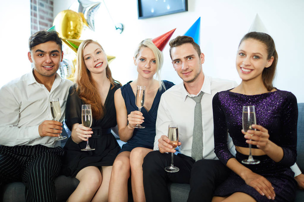 Efektowne dziewczyny i faceci w eleganckim stroju opiekania szampanem na imprezie urodzinowe w domu - Zdjęcie, obraz