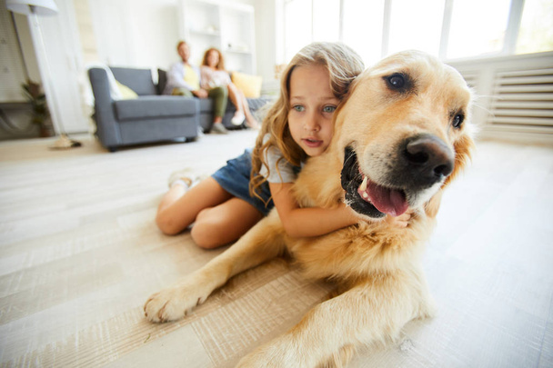 Restful purebred labrador and cute little girl lying on the floor of living-room at leisure - Foto, afbeelding