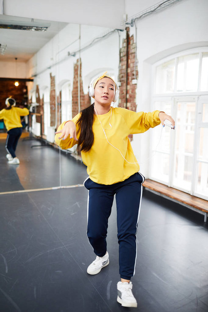 Young dancer in activewear learning hip hop motion during training in modern studio of dancing - Photo, Image