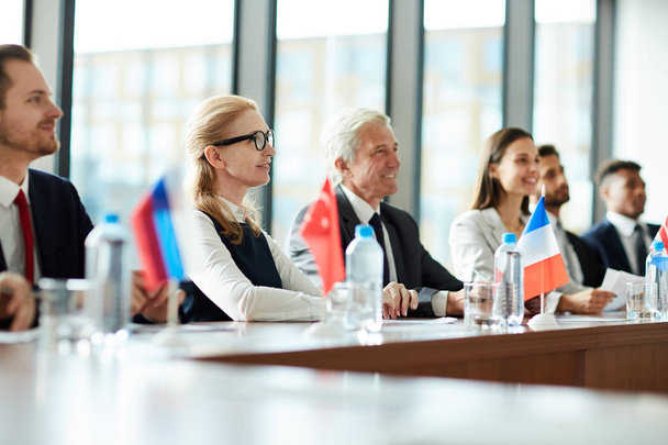 Fila de participantes extranjeros en cumbre política sentados a mesa larga con sus banderas delante
 - Foto, Imagen