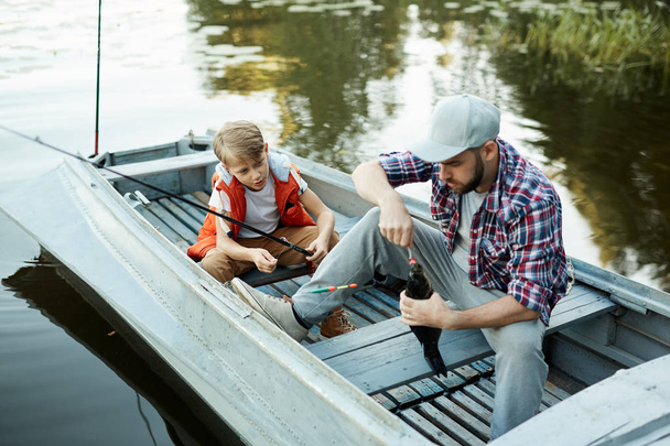 Isä kalastamassa veneessä poikansa kanssa, he saavat ison kalan.
 - Valokuva, kuva
