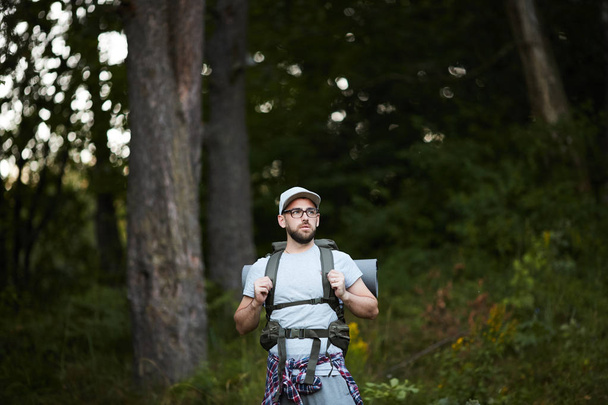 Młody aktywny Backpacker z plecakiem za plecami patrząc na bok, szukając właściwej drogi - Zdjęcie, obraz