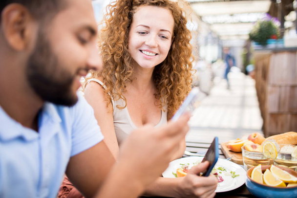 Ritratto di donna moderna sorridente felicemente mentre chatta con un amico seduto al tavolo del caffè all'aperto, copiare lo spazio
 - Foto, immagini