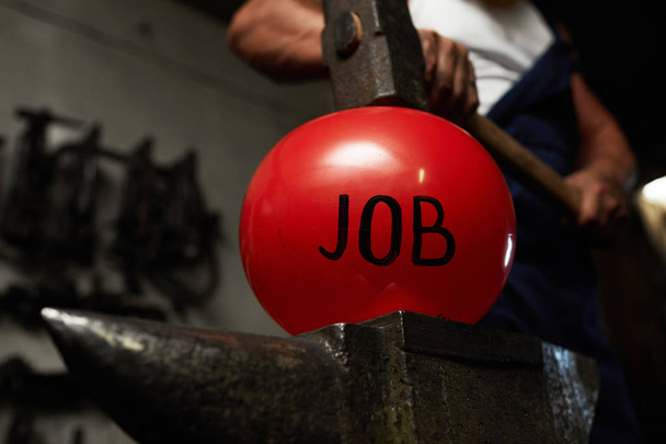 Forgeron gardant marteau lourd sur boule gonflée rouge symbolisant le travail
 - Photo, image