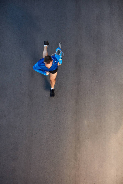 Top view of man running on the street. On arm smart phone. healthy lifestyle concept. - Фото, зображення