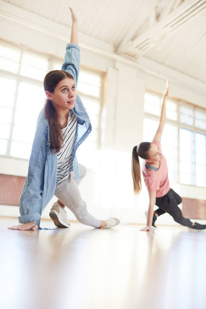 Aktivní dívky provádějící taneční cvičení nebo posunout po jejich trenér na lekci moderní breakdance ve studiu - Fotografie, Obrázek