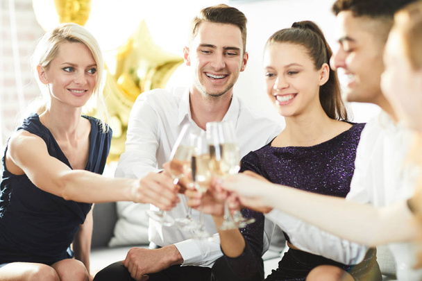 Amigos alegres en ropa elegante tostadas con flautas de champán en la fiesta
 - Foto, Imagen
