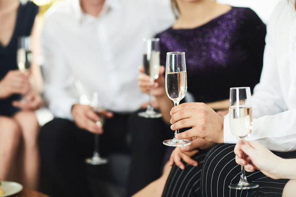 Emberi kéz tartó fuvolára pezsgővel beszélgetés közben a társasági összejövetelen - Fotó, kép