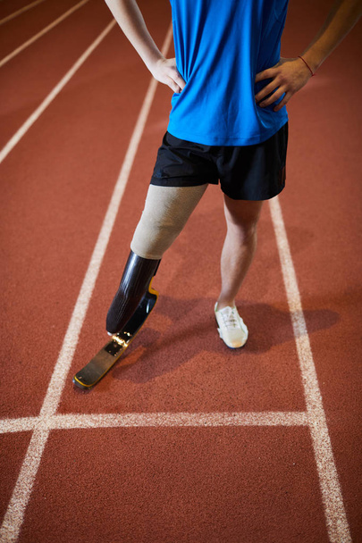 Low section of paralympic sportsman standing on race track by start line before competition or marathon - Photo, Image