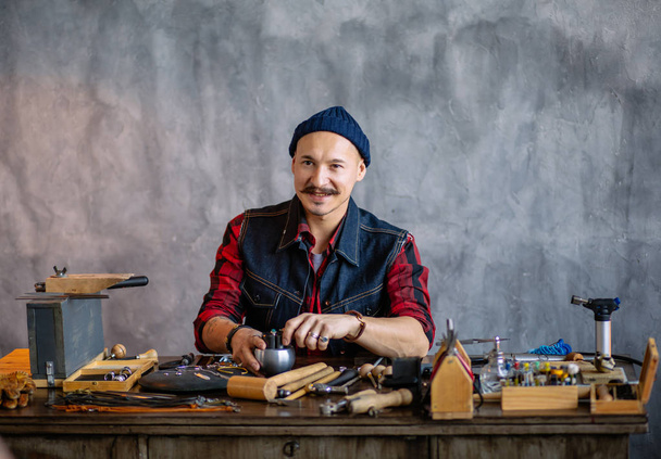 positive attractive man creating a design while working in the jewelry shop - Foto, afbeelding