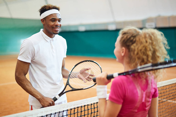 Kaksi nuorta kulttuurienvälistä tennispelaajaa mailat valmiina net ennen peliä
 - Valokuva, kuva