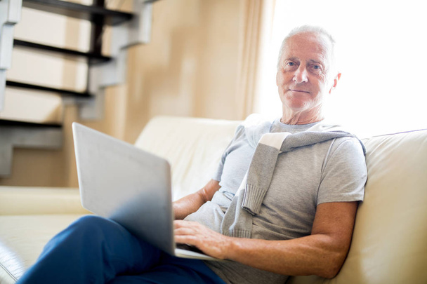 Hombre de edad en ropa de casualwear mirando durante la red en el entorno del hogar
 - Foto, Imagen