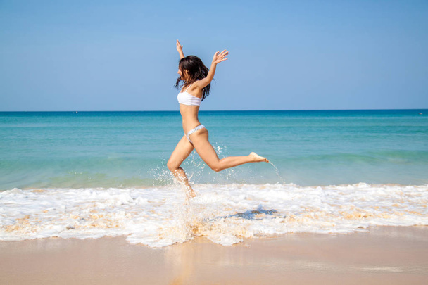 Felice donna asiatica che salta sulla spiaggia tropicale esprimendo la sua libertà
. - Foto, immagini