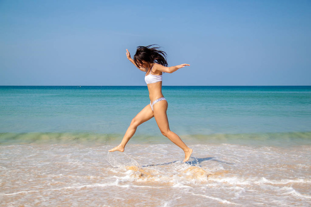 Szczęśliwa kobieta Azji skoki na tropikalnej plaży wyrażania jej wolności. - Zdjęcie, obraz