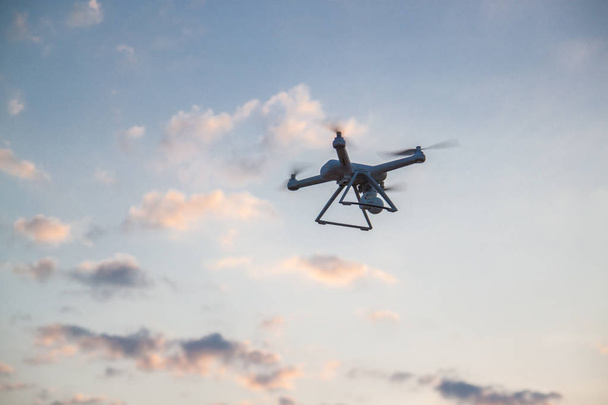 Concept photo and video with the help of the drone with the air in nature. Pink background. Copy space. A quadrocopter flies in the sunset with beautiful clouds. - Photo, Image