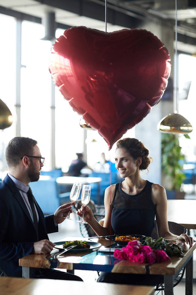 Счастливая влюбленная пара, звенящая на флейтах шампанского, наслаждаясь романтическим свиданием в ресторане
 - Фото, изображение