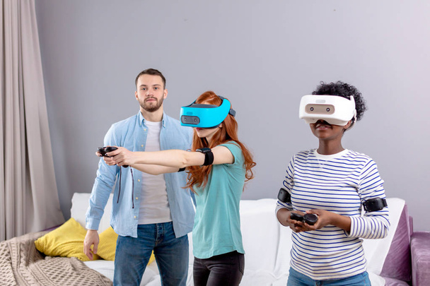 Multicultural group of friends playing games using virtual reality glasses. - Фото, изображение
