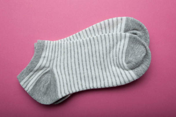 Gray female socks in stripes on a pink background. - Foto, afbeelding