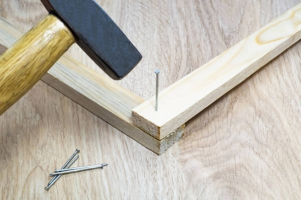 Hammer hammers a nail into a wooden block. - Photo, image