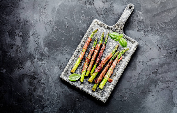 top view of fresh organic asparagus wrapped in parma ham on grey surface - Фото, зображення