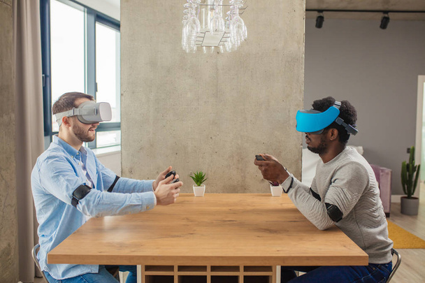 Two diverse man in casual wear are developing a project using virtual reality goggles. - Foto, Bild