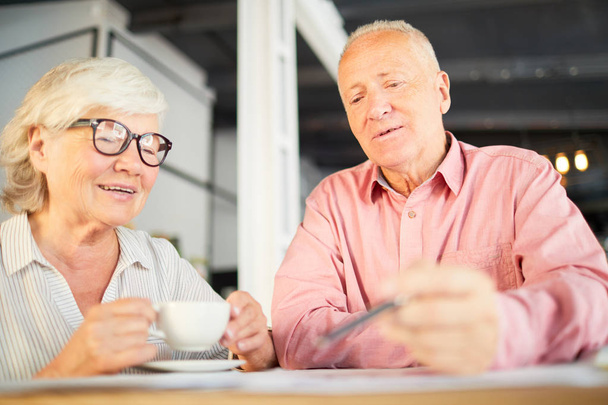 Donna d'affari anziana in occhiali e il suo collega discutono punti di nuovo contratto mentre bevono in caffè
 - Foto, immagini