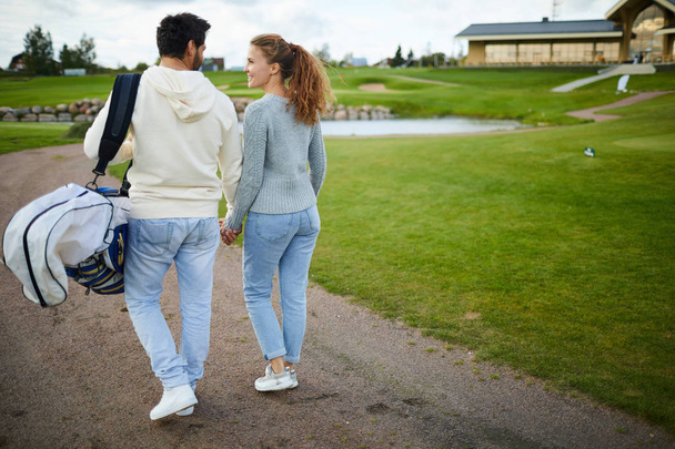 Nuoret rento pari tilalla käsin keskustellessaan golf pelata matkalla kotiin
 - Valokuva, kuva