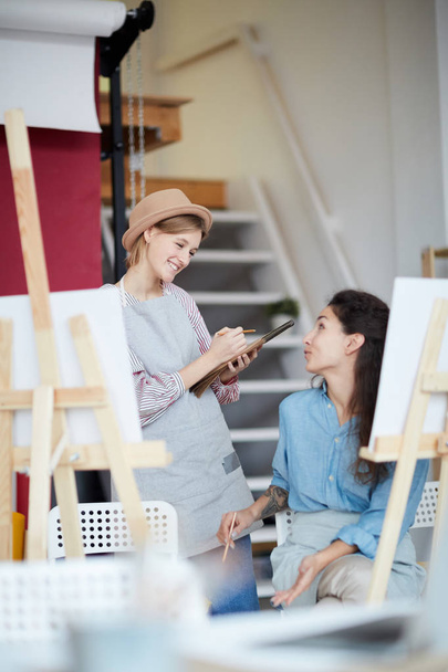 Twee jonge creatieve vrouwen bespreken hun ideeën voor het schilderen in Studio of Arts - Foto, afbeelding
