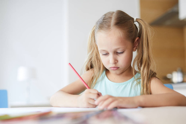 Chica bastante seria dibujo con lápices de colores en el ocio durante su estancia en casa
 - Foto, Imagen