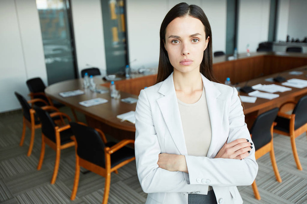Waist up portrait of confident businesswoman looking at camera with serious face expression while posing in office with arms crossed, copy space - Foto, imagen