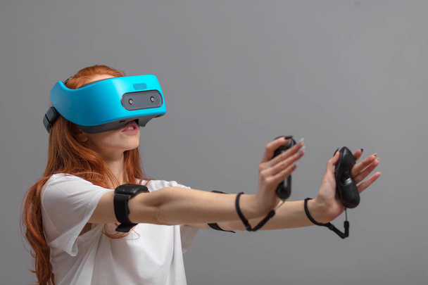 Redhead girl using VR glasses isolated over white. Virtual reality experience - Фото, изображение