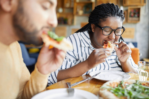 Two young hungry persons eating appetizing italian pizza in cafe during lunch break - Photo, Image