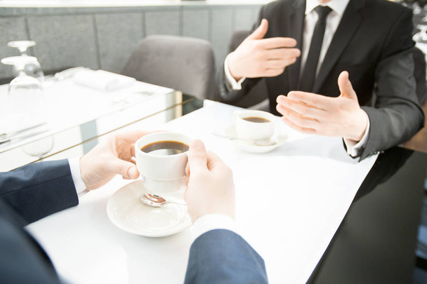Két ügynökök megvitatása új üzleti lehetőségeket csésze fekete kávé vagy tea étteremben ebédszünetben - Fotó, kép