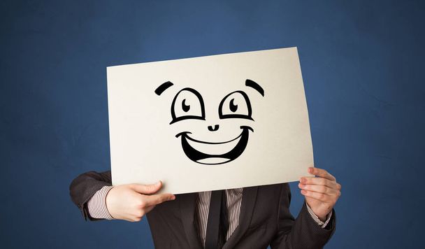 Osoba posiadająca papieru przed jego twarz z doodle emotikon - Zdjęcie, obraz