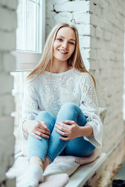 Portrait of beautiful woman sitting on the window sill and smiling. - Foto, imagen