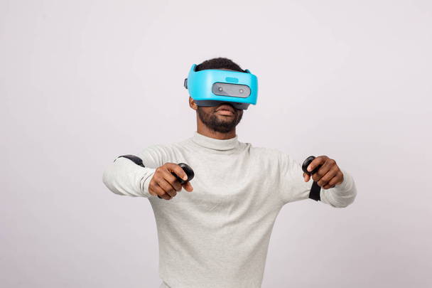 Jonge Afrikaanse man dragen VR bril geïsoleerd op witte achtergrond - Foto, afbeelding