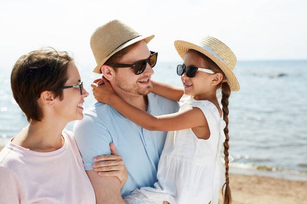 夏休み中にビーチで散歩を楽しむ幸せな現代の家族の暖かいトーンの肖像画 - 写真・画像