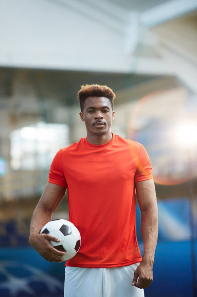 Mladý fotbalista v červené tričko postavení s fotbalovým míčem na moderní stadion - Fotografie, Obrázek