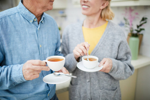 Senior małżonków z filiżanek herbaty o rozmowy w kuchni przez śniadanie - Zdjęcie, obraz