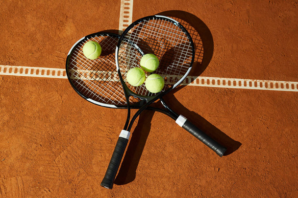 Overview of two tennis rackets with group of balls on top lying on court at stadium - Foto, Imagen