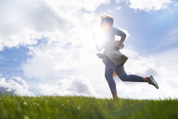 Активная молодая женщина бегает по горизонту под солнцем на облачном небе в естественной среде
 - Фото, изображение
